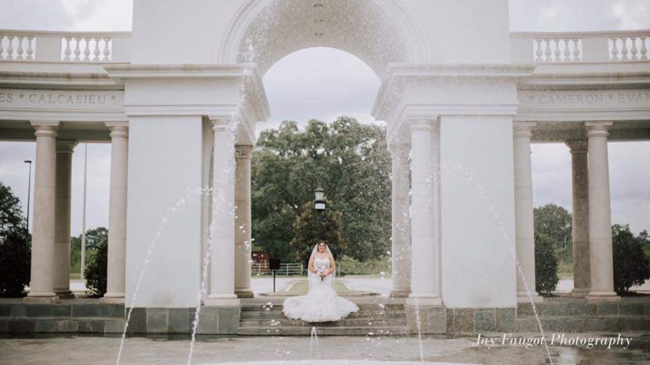 Picture of a bride under the arch of the Colonnade with fountain in from - Reception Venues - Lafyette La - Le Pavillon